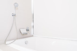 Modern bathroom with a sleek bathtub, showerhead, and minimalistic design, highlighting plumbing fixtures relevant to shared living situations.