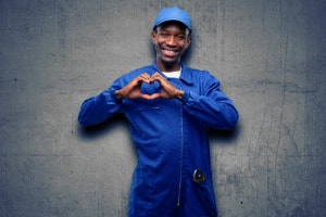 Plumber in blue uniform making a heart shape with hands, promoting plumbing services and love in shared living situations.