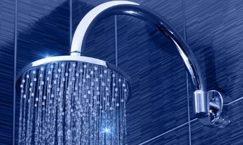Eco-friendly showerhead with water cascading, highlighting water-saving technology, in a modern bathroom setting.