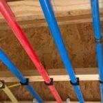 Colorful pipes secured on wooden panels for plumbing setup by Lodder Brothers Limited.