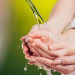 Hands gently gripping flowing water, emphasizing plumbing safety and clean water benefits for homeowners.