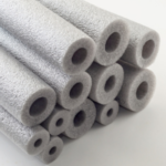 Stack of grey foam tubes with circular openings, used for plumbing insulation by Lodder Brothers Limited.