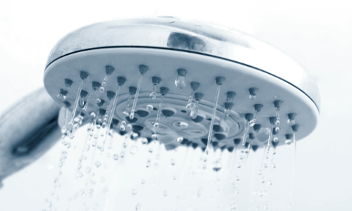 Showerhead with water droplets illustrating inconsistent water temperature issues related to water heater performance.