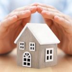 Hands protecting a wooden house model, emphasizing gas leak safety by Lodder Brothers Limited.