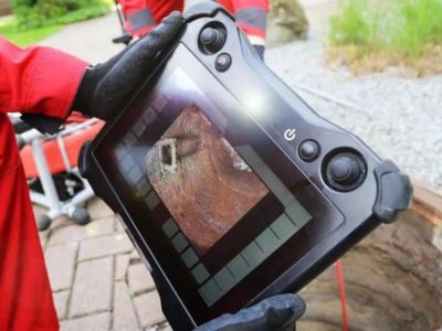 Plumber using a tablet displaying high-resolution sewer camera inspection images, showcasing plumbing diagnostics for clogs and leaks.