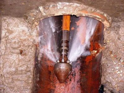 High-pressure hydro jetting nozzle blasting water to clear clogs in a sewer pipe, demonstrating effective drain cleaning method.