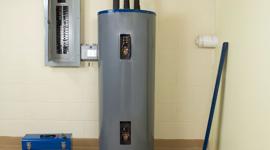 Water heater unit in residential setting with visible plumbing connections and electrical panel, illustrating essential maintenance for efficient operation and service needs.