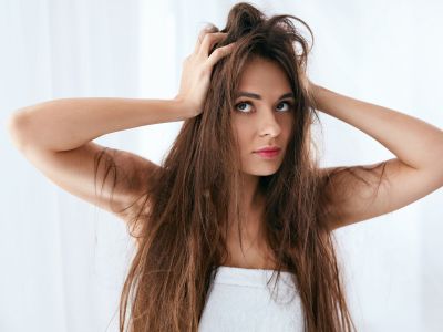 Woman with long, unkempt hair expressing frustration, illustrating the effects of hard water on hair and skin.