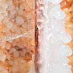 Frozen pipe with ice buildup and dripping water, illustrating the risks of inadequate insulation and winterization for plumbing systems.