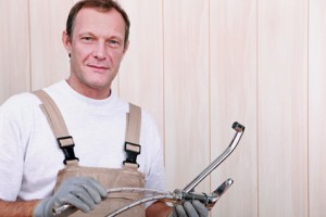 Plumber holding plumbing fixtures and tools, emphasizing professional plumbing services and preventive maintenance.