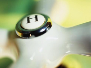Close-up of a white faucet handle labeled "H" for hot water, illustrating plumbing fixtures relevant to gas line safety and maintenance.