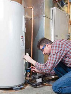 Person wearing safety goggles adjusting the regulator on a water heater, demonstrating maintenance procedures for optimal water heating performance.